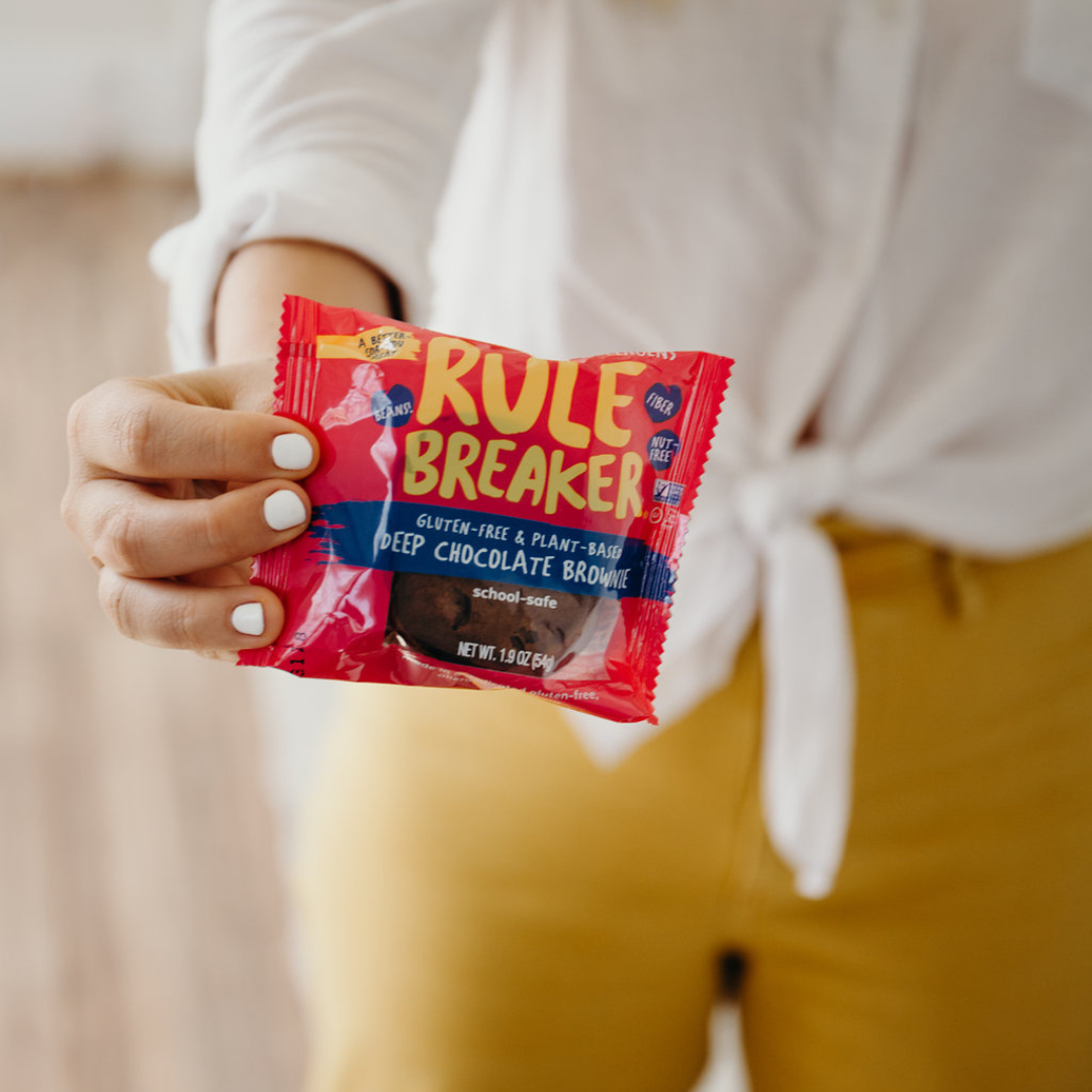 Woman holding Rule Breaker Snacks vegan gluten free allergen free vegan Brownie made with chickpeas