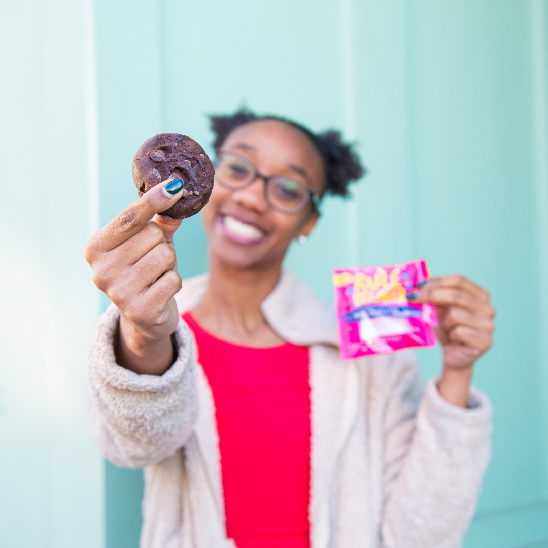 Woman holding Rule Breaker Snacks vegan gluten free allergen free vegan Brownie made with chickpeas