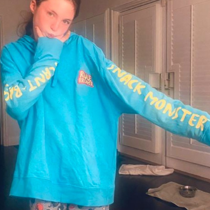 A girl wearing a blue Rule Breaker  Snack Monster hoodie