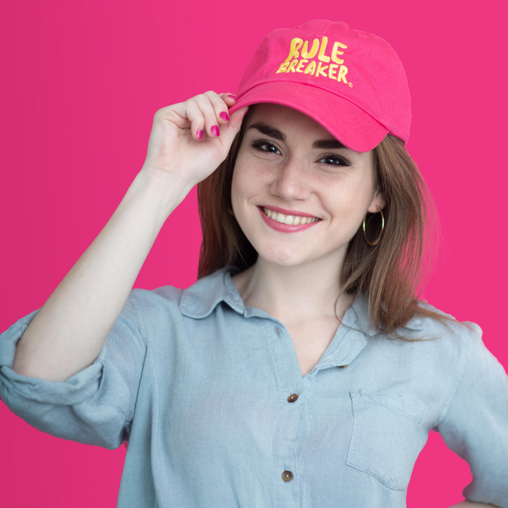 Woman wearing a pink hat with yellow rule breaker logo