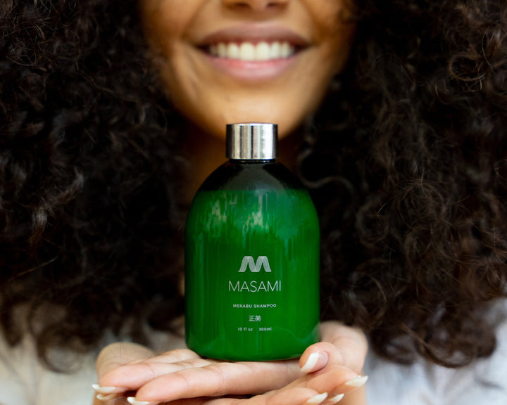 Woman with curly hair holding MASAMI shampoo