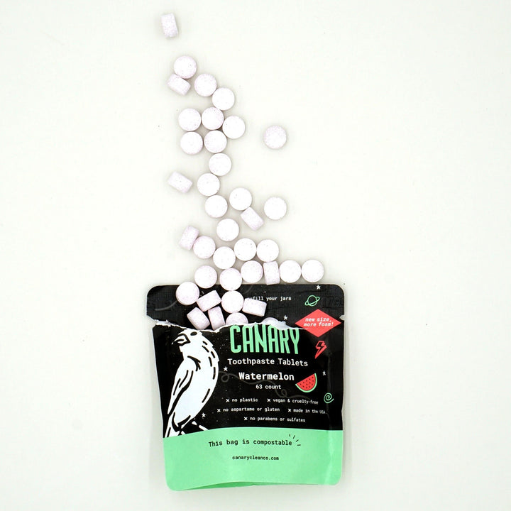 Canary Watermelon Toothpaste Kid-friendly Tablets, sample size 63 count compostable pouch, with tablets spilling out of the open pouch 