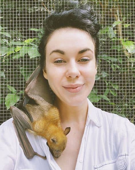 A fruit bat resting on a woman's shoulder